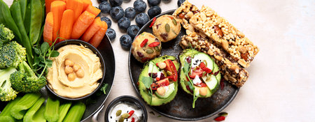 Various hummus dips. Hummus plate with vegetable snacks. Carrot, celery sticks. Vegan and traditional hummus as healthy and vegan snack on a light background. Top view.の写真素材
