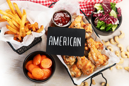 Fried chicken wings with dip, fries and salad on a light background. Top view.