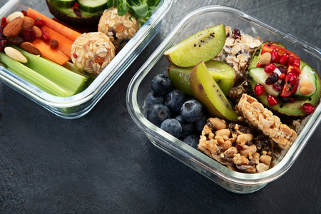 Lunchboxes with various healthy nutritious meals. Concept of healthy snacks in boxes on a dark...