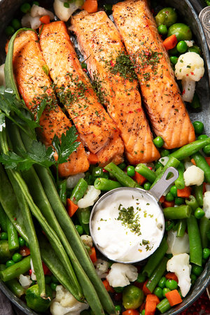 Grilled salmon steak with organic vegetables, salad and dessert on a light background. Top view.の写真素材