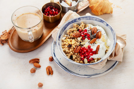 Homemade granola with Greek yogurt, fresh berries and honey on white background. Top view. Healthy...