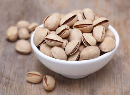 Bowl of pistachios on wooden backgroundの写真素材