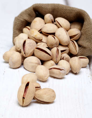 Bag of pistachios on white wooden background