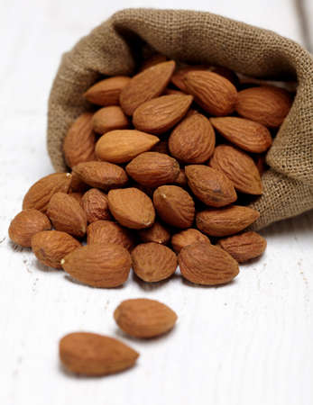 Bag of almonds on white wooden backgroundの写真素材