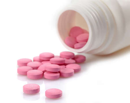 Pink pills pouring out from bottleの写真素材