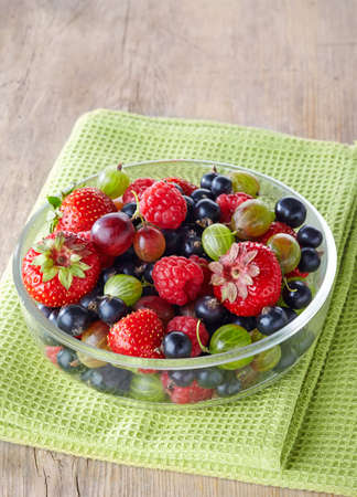 Bowl of fresh ripe berries on green tableclothの写真素材
