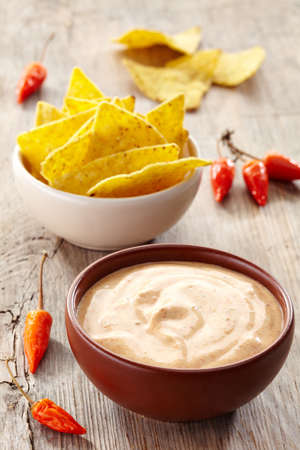 Bowl of dip and bowl of nachos on wooden backgroundの写真素材