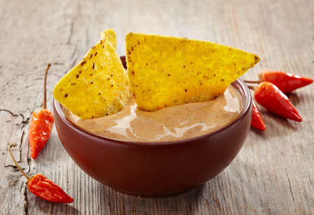 Bowl of dip and nachos on wooden backgroundの写真素材