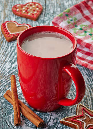 Red mug of hot chocolate drink with cinnamon sticks and gingerbread cookiesの写真素材