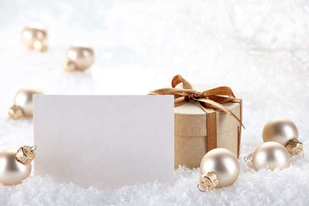 Golden Christmas decorations and gift with blank card in snowの写真素材