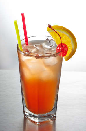 Orange cocktail with straws decorated with slice of orange and cherryの写真素材