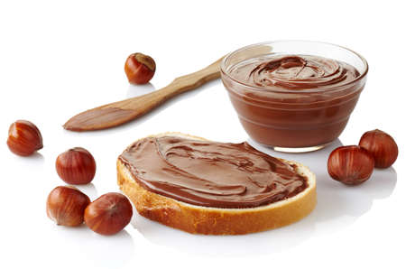 Slice of bread with chocolate cream and hazelnuts isolated on white の写真素材