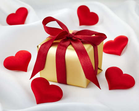 Golden gift box with red ribbon and heartsの写真素材