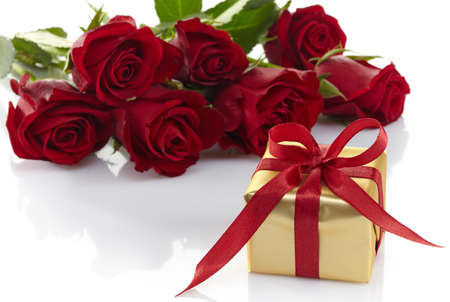 Golden gift box and bouquet of red roses isolated on white backgroundの写真素材