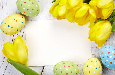 Colorful Easter eggs, tulips and blank card on wooden backgroundの写真素材