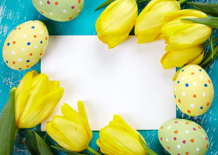 Colorful Easter eggs, tulips and blank card on blue wooden backgroundの写真素材