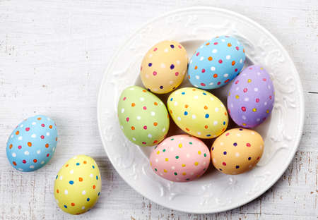 Plate of colorful Easter eggs on white wooden backgroundの写真素材