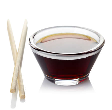 Bowl of soy sauce and two chopsticks isolated on white backgroundの写真素材