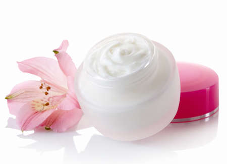 White jar with pink lid of cosmetic cream and flower isolated on white backgroundの写真素材