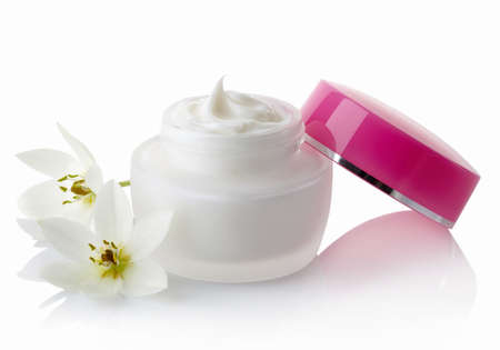 White jar with pink lid of cosmetic cream and flowers isolated on white backgroundの写真素材