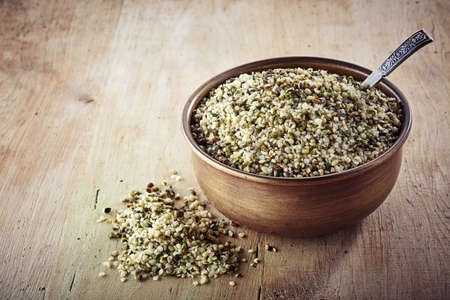 Bowl of shelled hemp seeds on wooden backgroundの写真素材