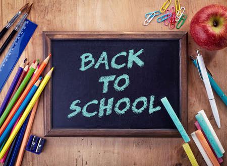 Chalkboard with back to school text and school office supplies on wooden background.の写真素材