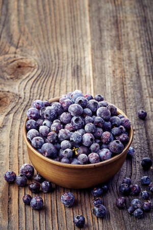 Frozen blueberries in a metal bowl on wooden backgroundの写真素材