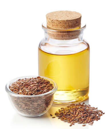 Bottle of linseed oil and bowl of linseeds isolated on white backgroundの写真素材