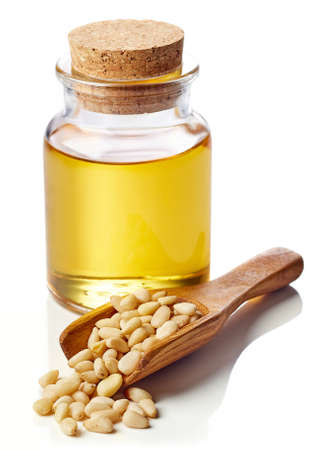 Bottle of pine nut oil and wooden scoop of pine nuts isolated on white backgroundの写真素材