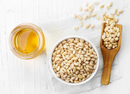 Pine nut oil and bowl of pine nuts on white wooden background. Top viewの写真素材