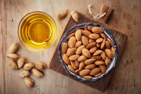 Almond oil and bowl of almonds on wooden background. Top viewの写真素材