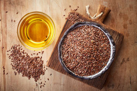 Linseed oil and bowl of linseeds on  wooden background. Top viewの写真素材
