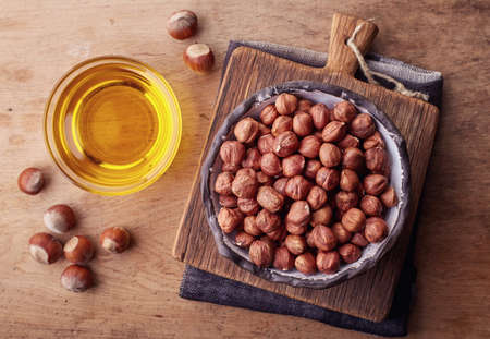 Bowl of hazelnut oil and hazelnuts on wooden background. Top viewの写真素材