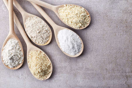 Wooden spoons of various gluten free flour (almond flour, amaranth seeds flour, buckwheat flour, rice flour, chick peas flour) from top viewの写真素材