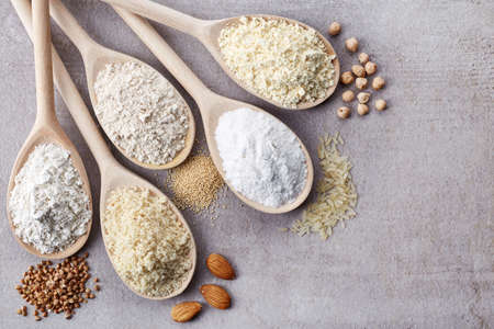 Wooden spoons of various gluten free flour (almond flour, amaranth seeds flour, buckwheat flour, rice flour, chick peas flour) from top viewの写真素材