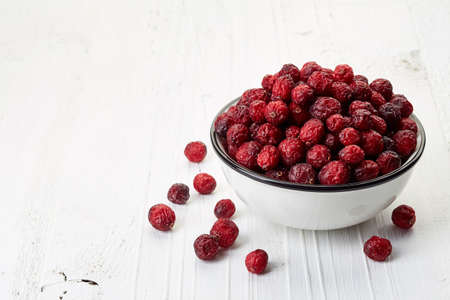 Bowl of dried cranberries on white wooden backgroundの写真素材