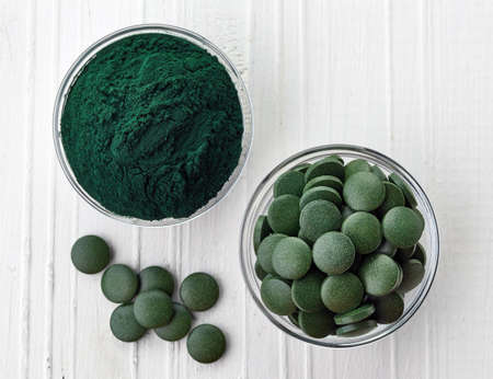Spirulina algae powder and tablets on white wooden background from top viewの写真素材