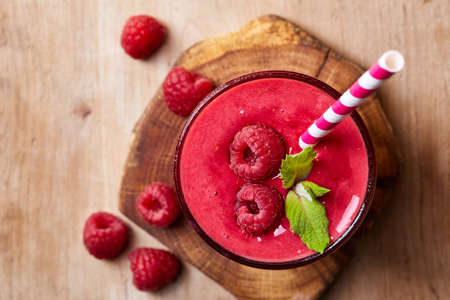 Glass of raspberry smoothie on wooden background from top viewの写真素材