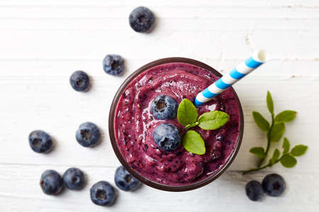 Glass of blueberry smoothie on white wooden background from top viewの写真素材