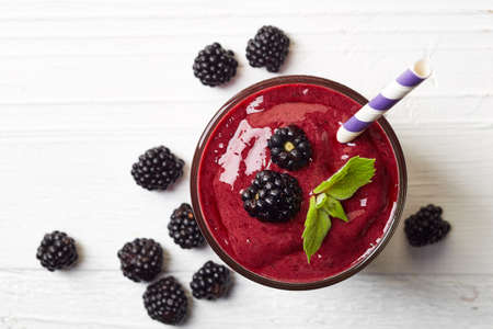 Glass of blackberry smoothie on white wooden background from top viewの写真素材