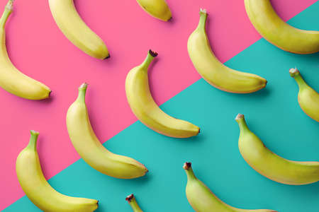 Colorful fruit pattern of fresh yellow bananas on pink and blue background. From top viewの写真素材