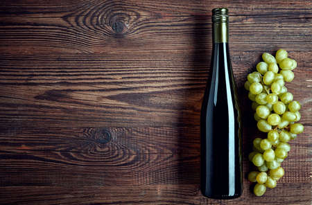 Bottle of white wine and grapes on wooden background from top viewの写真素材