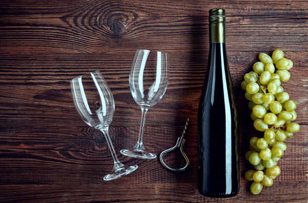 Bottle of white wine, two glasses and grapes on wooden background from top viewの写真素材