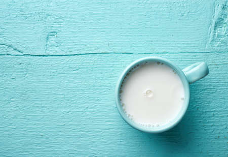 Blue cup of fresh milk on wooden background. Top view.の写真素材