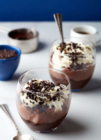 Two glasses of chocolate parfait dessertand cup of coffee on white marble tableの写真素材