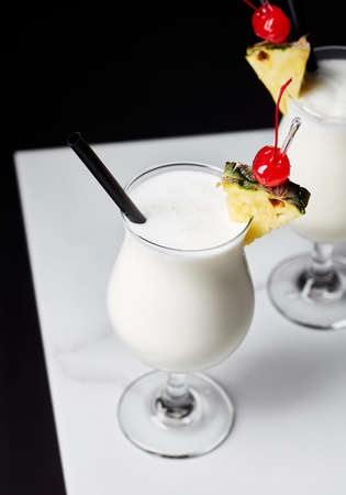 Two glasses of Pina Colada cocktail on white marble tableの写真素材