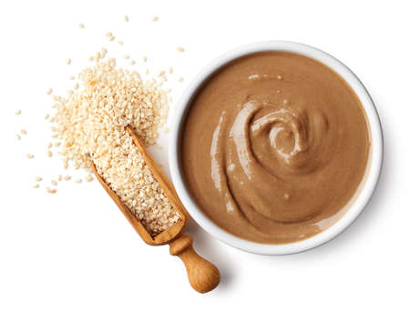 Bowl of tahini sauce and sesame seeds isolated on white background. Top viewの写真素材