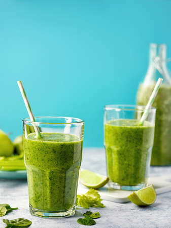 Fresh healthy green fruit and vegetable smoothies on blue background