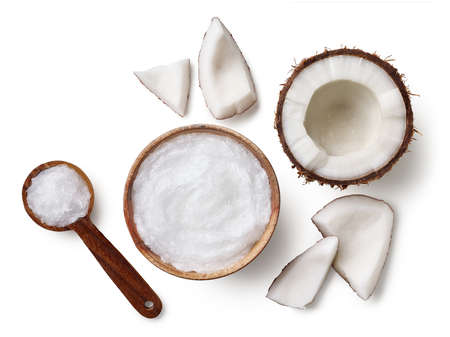 Wooden bowl and spoon of coconut oil and fresh coconut pieces isolated on white