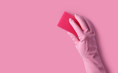 Hand with robber glove washing pink wall with sponge, empty space for textの写真素材